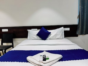 A hotel room with a bed, a chair, and a blanket. - Orion Signature Hotel  (Hyderabad)
