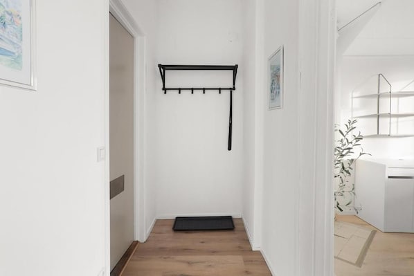 A hallway with a black coat rack, a door, and a small mat on the floor.