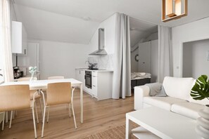 A modern kitchen with white cabinetry, a marble countertop, and a stainless steel range hood.