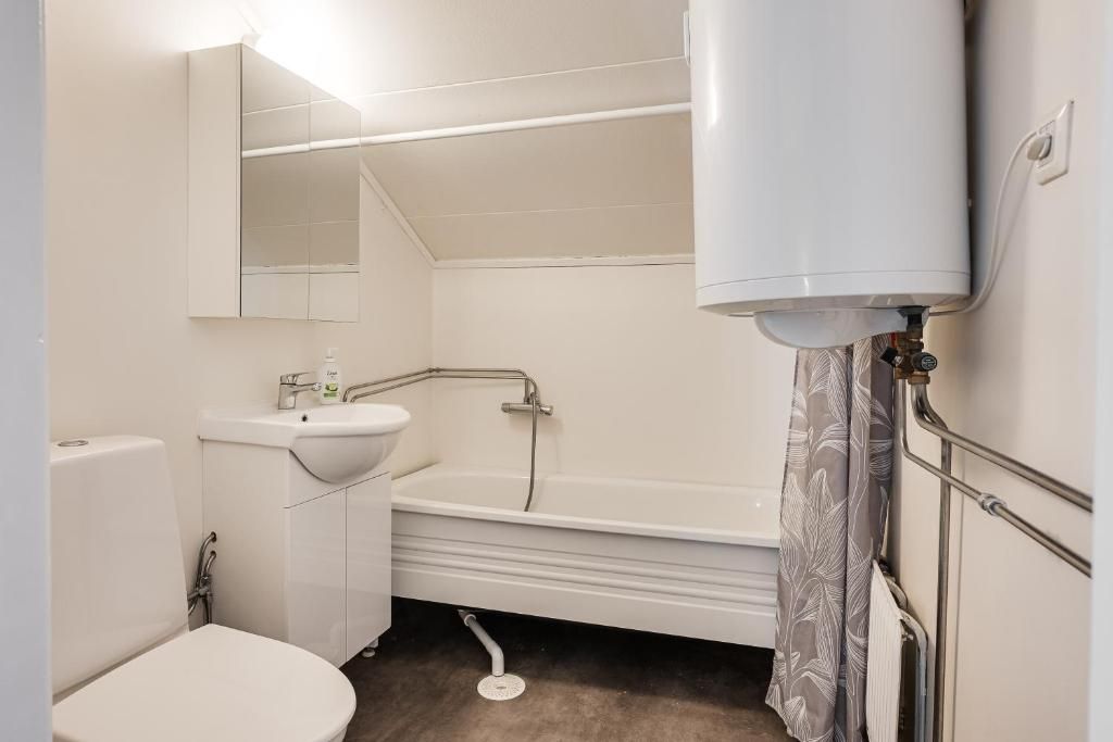 Et badeværelse med toilet, håndvask og badekar.