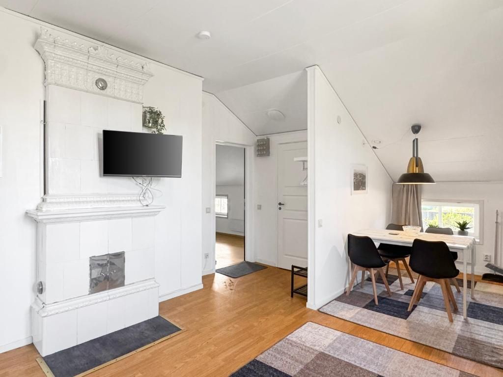 En moderne stue med pejs, et fladskærms-tv, et spiseområde med bord og stole, og en trappe der fører til et andet rum.