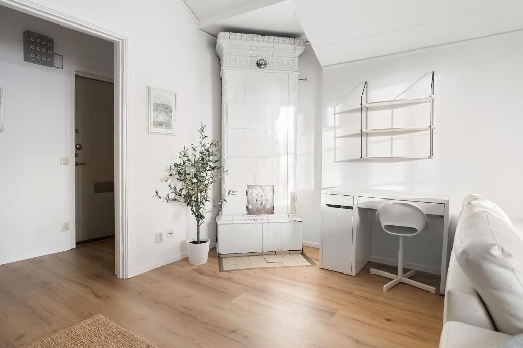 Een moderne, minimalistische kamer met een houten vloer, een wit bureau, een witte stoel en een witte bank.