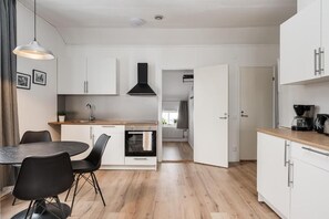 A modern kitchen with white cabinets, a black range hood, and a dining area with a round table and chairs.