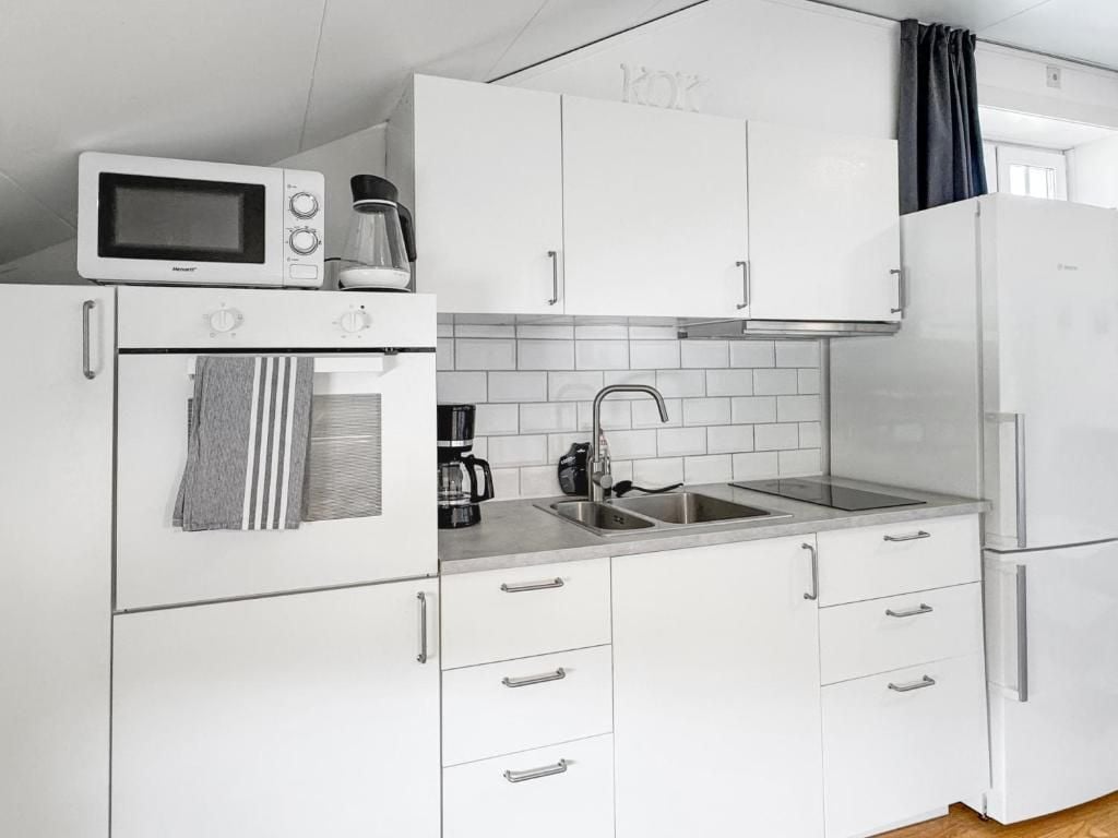 A compact kitchen with white cabinets, a microwave, a coffee maker, and a refrigerator.