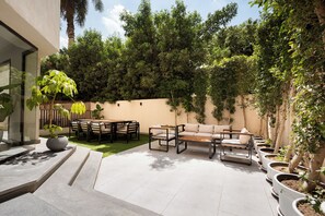 A patio with a dining table, chairs, and a sofa. - Cozy Corner at Elevens by spacey #29 (cairo)