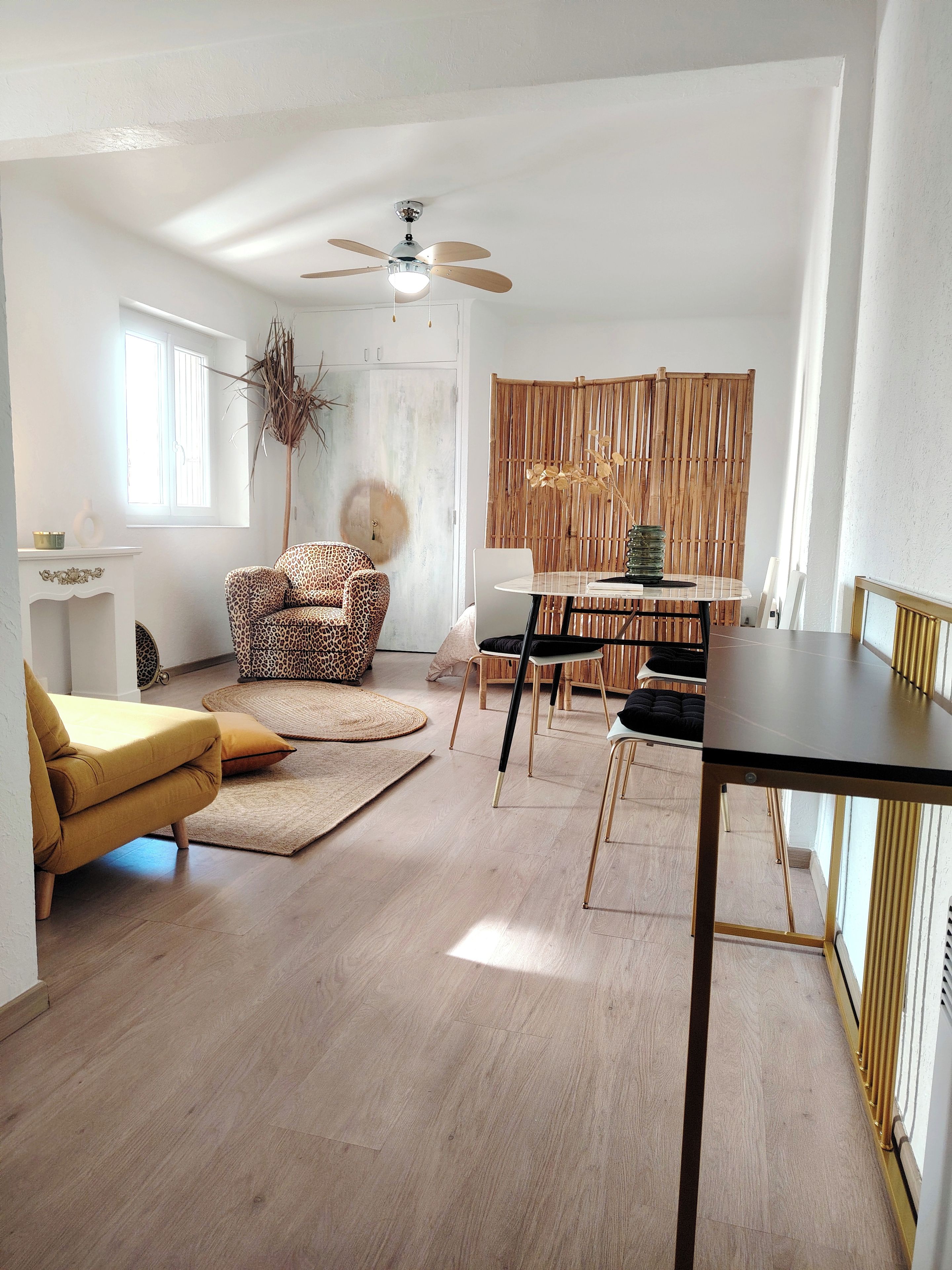 A modern living room with a sofa, a dining table, and a ceiling fan.