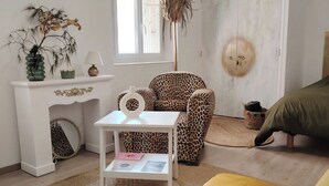 A room with a white sofa, a leopard print chair, a small white table with a lamp, a decorative plant, and a ceiling fan. - Apartment in downtown Toulon, between the port and the train station (Toulon)