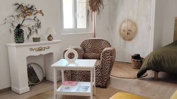 A room with a white sofa, a leopard print chair, a small white table with a lamp, a decorative plant, and a ceiling fan.