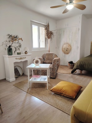 A room with a white sofa, a leopard print chair, a small white table with a lamp, a decorative plant, and a ceiling fan. - Apartment in downtown Toulon, between the port and the train station (Toulon)