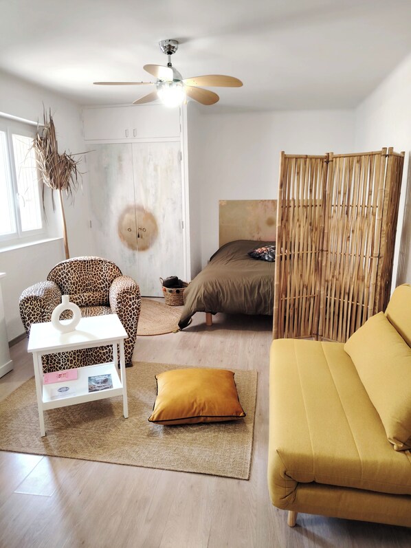 A room with a bed, a sofa, a small table, a decorative plant, and a ceiling fan. - Apartment in downtown Toulon, between the port and the train station (Toulon)