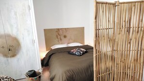A bedroom with a bed, a wardrobe, a bamboo partition, and a leopard print ottoman. - Apartment in downtown Toulon, between the port and the train station (Toulon)
