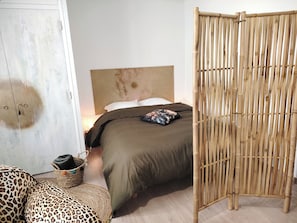 A bedroom with a bed, a wardrobe, a bamboo partition, and a leopard print ottoman. - Apartment in downtown Toulon, between the port and the train station (Toulon)