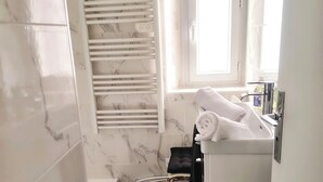 A bathroom with a white bathtub, a white sink with a mirror, and a black rug on the floor. - Apartment in downtown Toulon, between the port and the train station (Toulon)