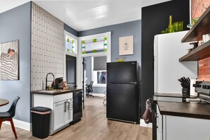 Een moderne keuken met een zwarte koelkast, witte kastjes en een houten vloer.