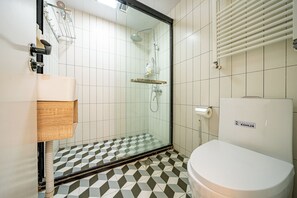 A bathroom with a shower, toilet, and a sink.