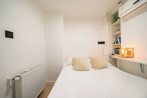 A bedroom with a bed, bedside table, lamp, and a radiator.