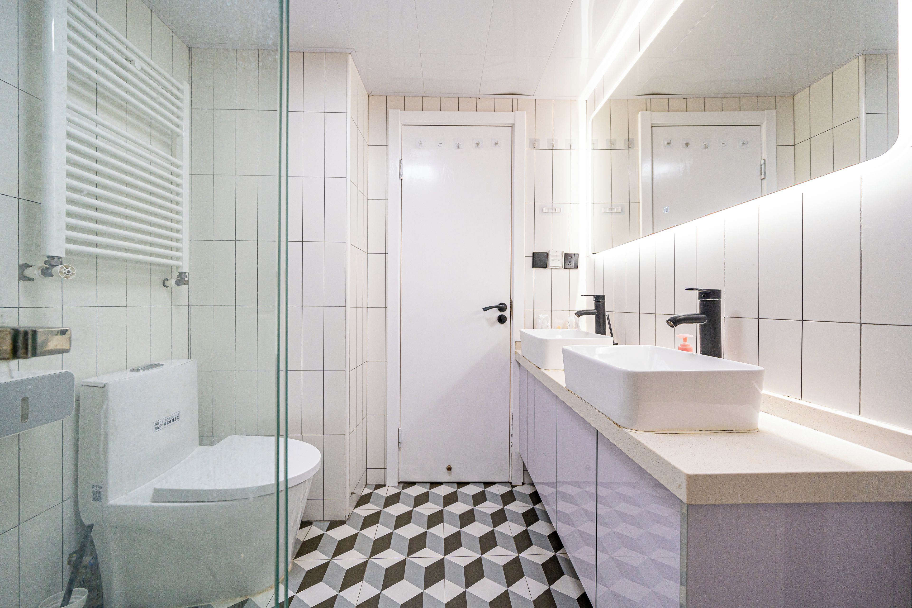 A modern bathroom with a toilet, bidet, and a large mirror above the sink.