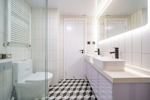 A modern bathroom with a toilet, bidet, and a large mirror above the sink.