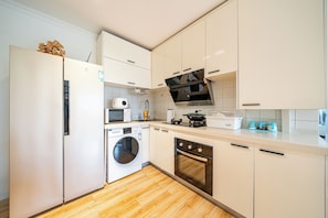 A modern kitchen with a built-in washer, oven, microwave, and a large stove.