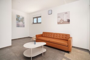 En moderne stue med en brun sofa, et hvidt sofabord og to billeder hængt på væggen.