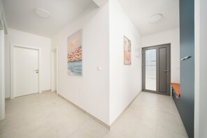 A hallway with white walls, a door on the left, and a door with a glass panel on the right. - Villa Pure (Šibenik)