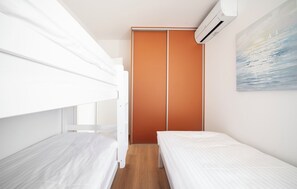 A bedroom with two bunk beds, a wardrobe, and an air conditioning unit. - Villa Pure (Šibenik)