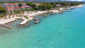 Et kystområde med klart turkis vand, en sandstrand og boliger med røde tage.
