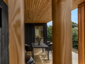 A wooden deck with a table and chairs, a potted plant, and a view of a garden. - "Munibert" - 100m from the sea by Interhome (Sjølund)