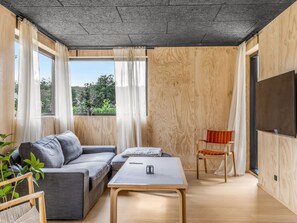 A modern living room with a grey sofa, a wooden coffee table, and a wooden chair. - "Munibert" - 100m from the sea by Interhome (Sjølund)