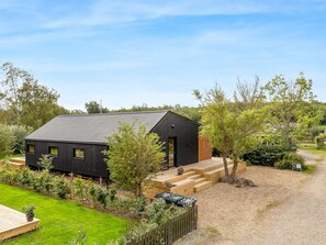 A modern black building with a sloped roof, surrounded by a well-maintained garden and a gravel path. - "Munibert" - 100m from the sea by Interhome (Sjølund)