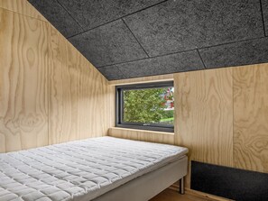 Ein Schlafzimmer mit einem Bett, einem Fenster und Blick ins Grüne.