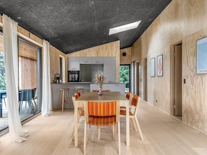 A modern kitchen with a central island, wooden flooring, and a dining area with a round table and chairs. - "Munibert" - 100m from the sea by Interhome (Sjølund)