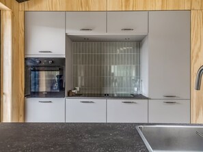 Eine Küche mit Backofen, gefliestem Spritzschutz und einer Spüle aus Edelstahl.