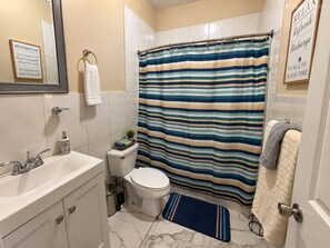 Un bagno con tenda da doccia a righe, un water, un lavandino e uno specchio.