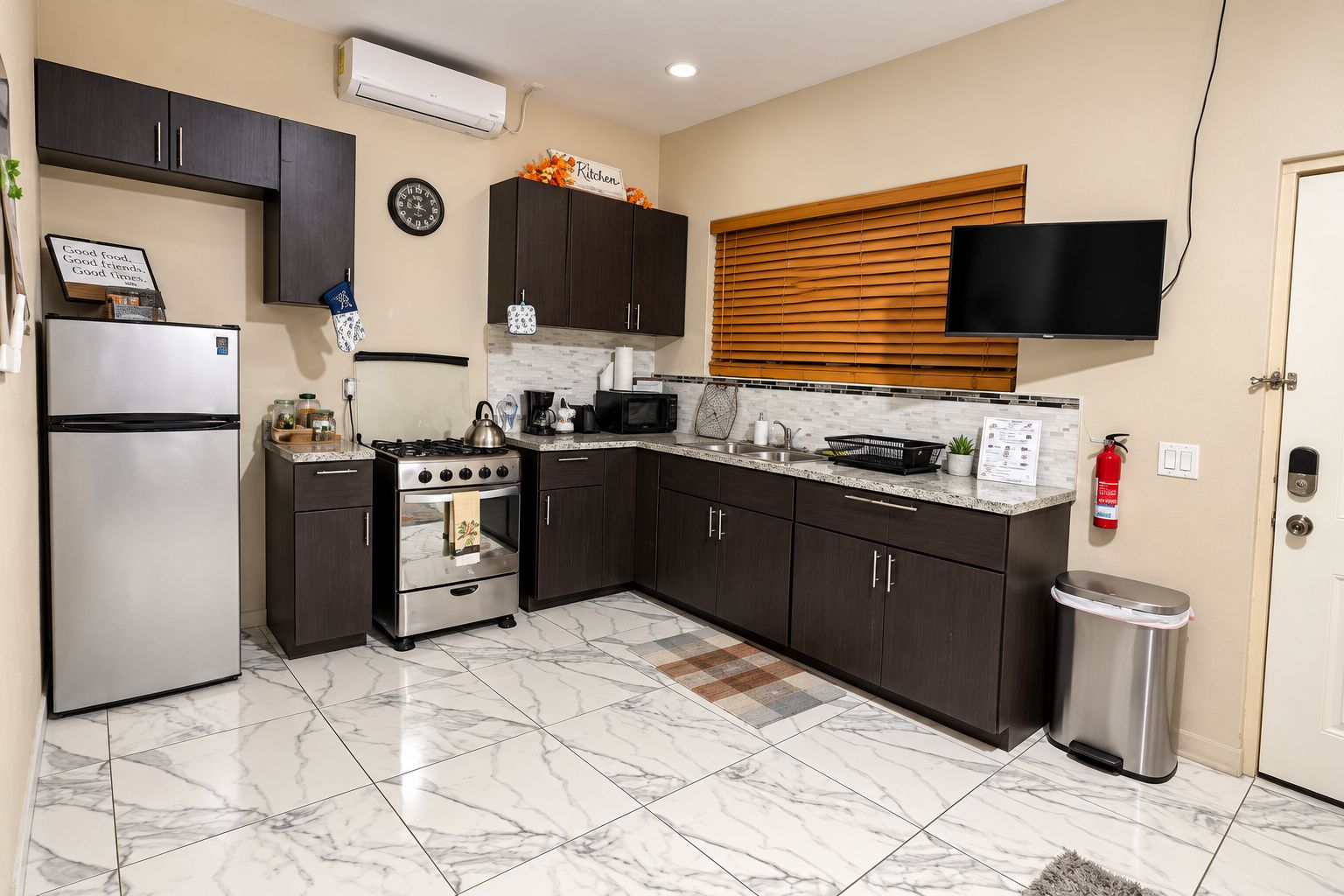 A modern kitchen with dark cabinets, a stainless steel refrigerator, an oven, a microwave, and a sink.