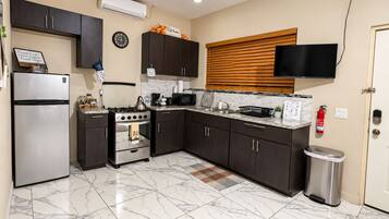 A modern kitchen with dark cabinets, a stainless steel refrigerator, an oven, a microwave, and a sink.
