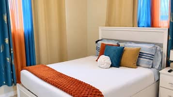 A hotel room with a bed, a nightstand, a drawer, an air conditioning unit, and curtains.
