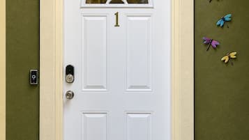 A white door with a number '1' above it, a keyhole, and a doorbell on the left.