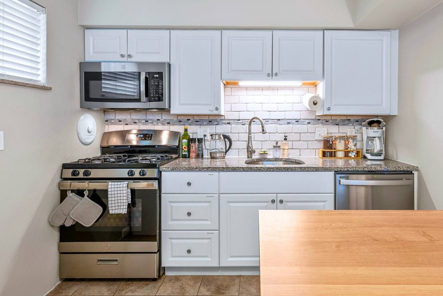 A kitchen with white cabinets, a stainless steel stove, a microwave, and a dishwasher.