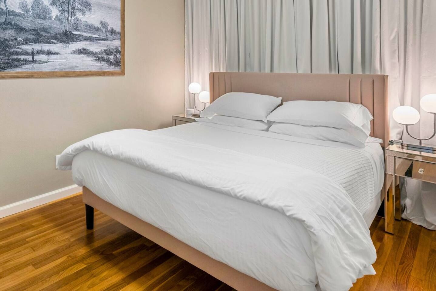 A neatly made bed with white bedding, a headboard, and bedside lamps.