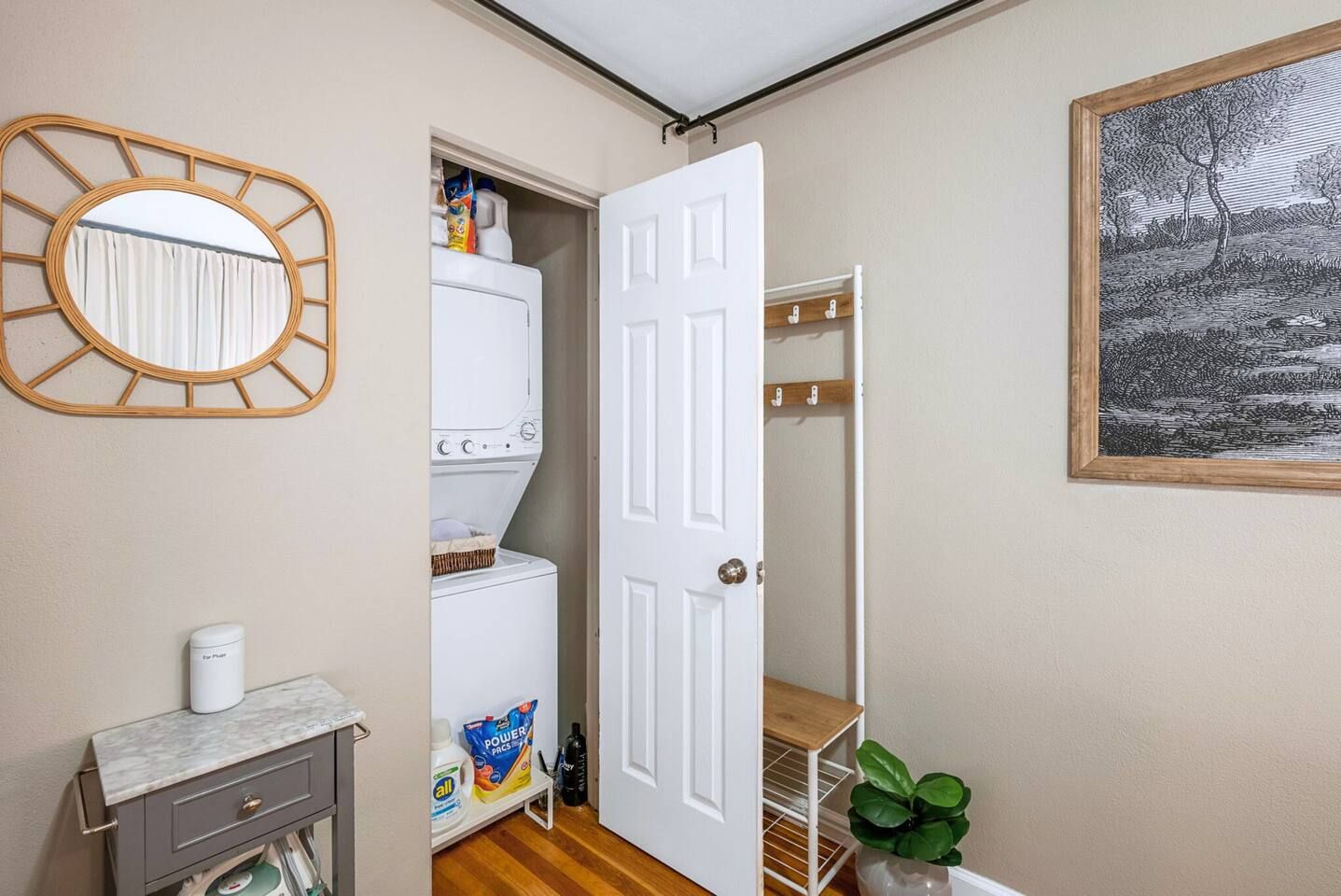 A laundry room with a washing machine, a drying rack, and a mirror.