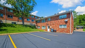A parking lot with a brick building adjacent to it. - Charming Kirkwood Two-Bedroom (St. Louis)