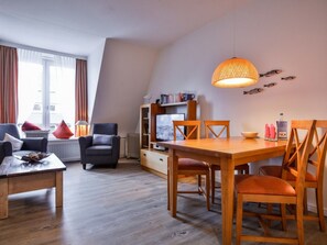 A modern living room with a dining area, a sofa, a TV, and a bookshelf. - Holiday Apartment With 1 Bedroom (Kampen)