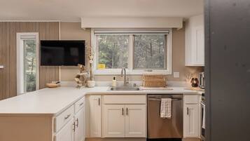 Een moderne keuken met een groot eiland, ingebouwde apparatuur en een raam met uitzicht op een bos.