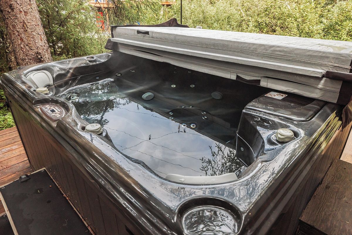 A hot tub with a wooden deck surrounding it, set in a natural outdoor environment.
