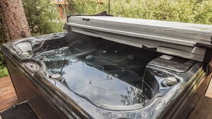 Un jacuzzi con un muelle de madera que lo rodea, en un entorno natural al aire libre.
