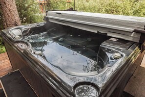 A hot tub with a wooden deck surrounding it, set in a natural outdoor environment. - Girdwood 2BR Retreat | Shared Hot Tub + Sauna (Anchorage)
