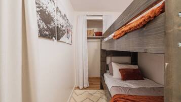 Een compacte kamer met een stapelbed, een kleine kitchenette en een deur naar een badkamer.