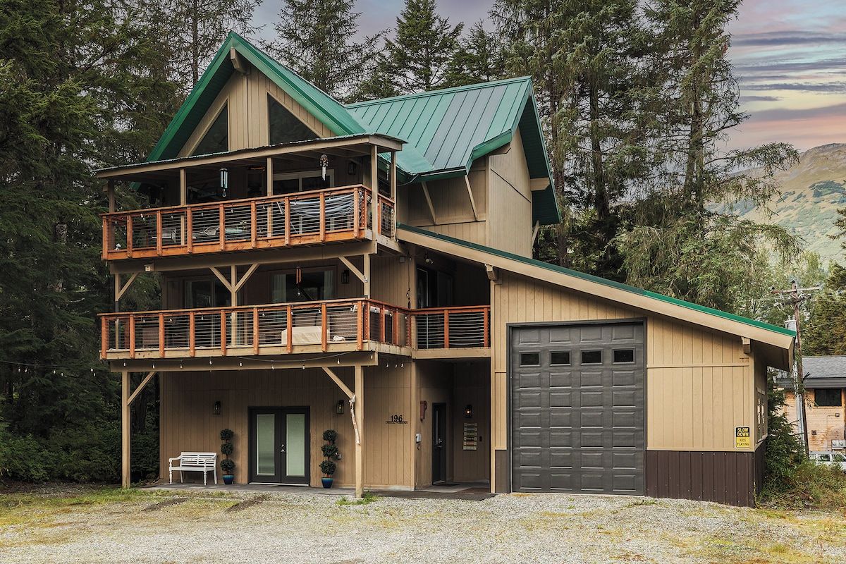 A multi-story building with a balcony, a garage, and a bench outside.