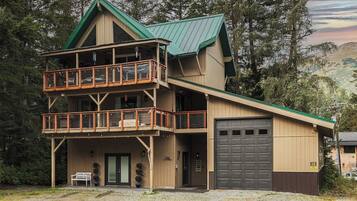 A multi-story building with a balcony, a garage, and a bench outside.
